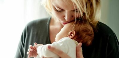 En dame holder en baby og kysser han på pannen