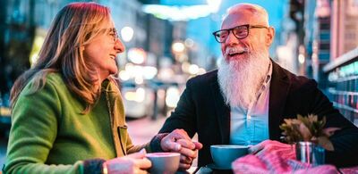 Et ektepar sitter på en cafe og smiler. Foto