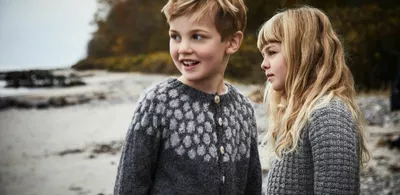 To barn står på en strand. Foto