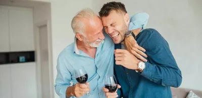 To menn holder rundt hverandre og ler. Foto