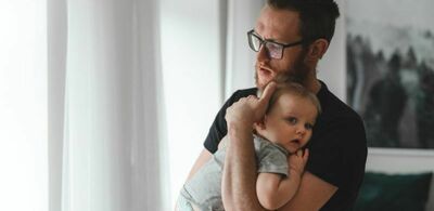 En mann holder en baby. Foto