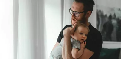 En mann holder en baby. Foto