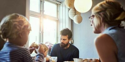 En familie på fire sitter rundt et frokostbord. foto