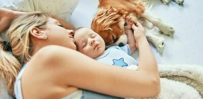 En dame holder rundt en baby og en hund. Foto