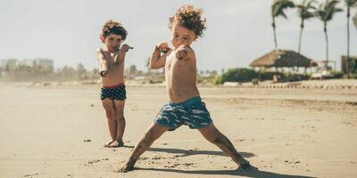 To barn står på en strand og peker. Foto