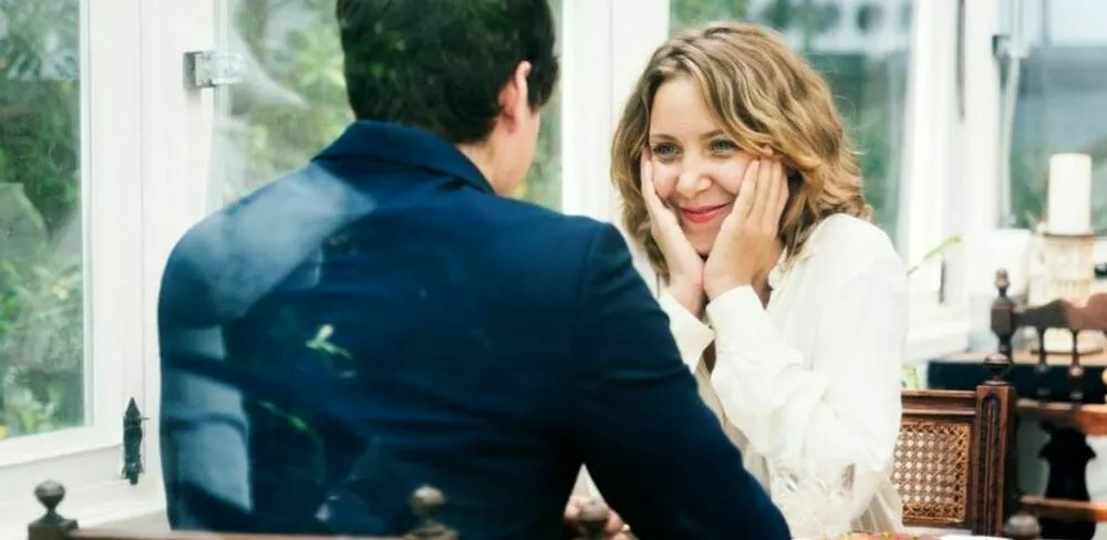 En dame sitter overfor en mann og smiler