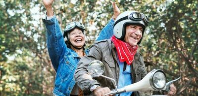 Et par sitter på en moped og smiler