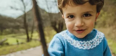 En liten gutt står ute i naturen