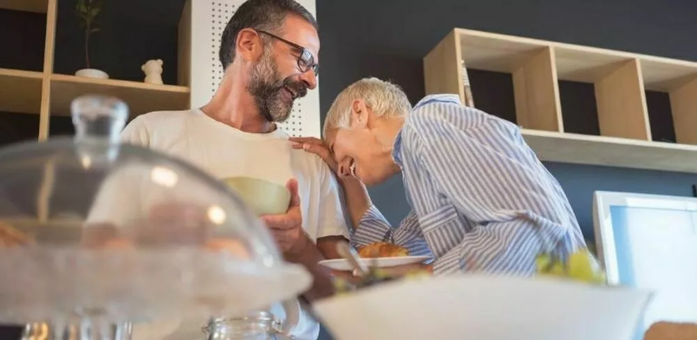 En dame lener seg på skulderen til en mann mens hun ler